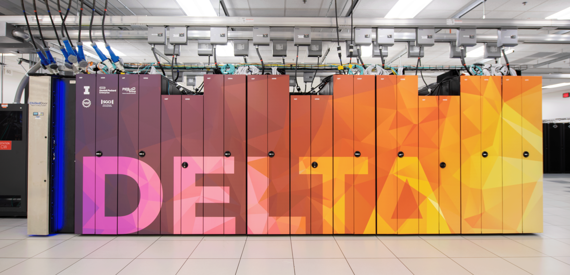 12 racks in a machine room, with overhead power, with red to orange "DELTA" wrap on the rack doors.